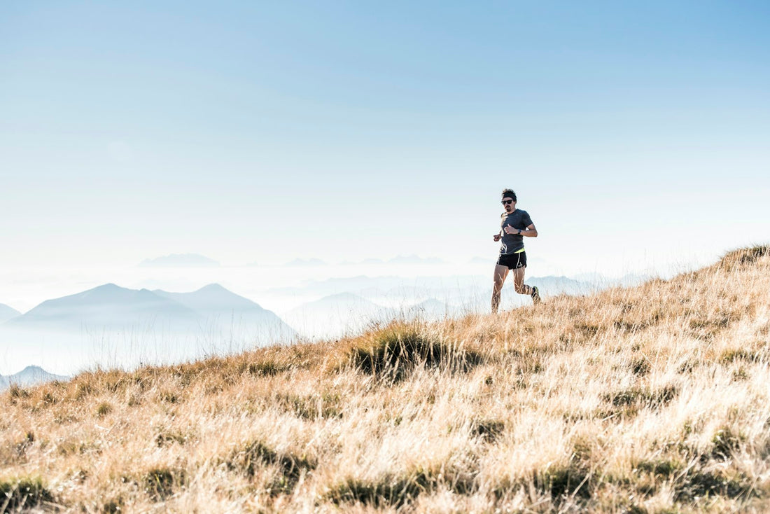 Coureur seul sur une crête herbeuse, au loin, sous un ciel dégagé
