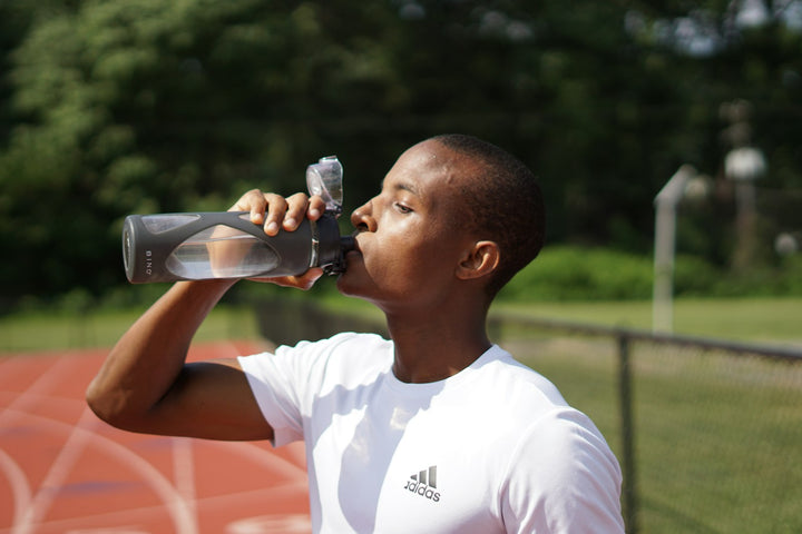 Athlète buvant à même une bouteille de sport après avoir préparé son mélange de boisson énergétique