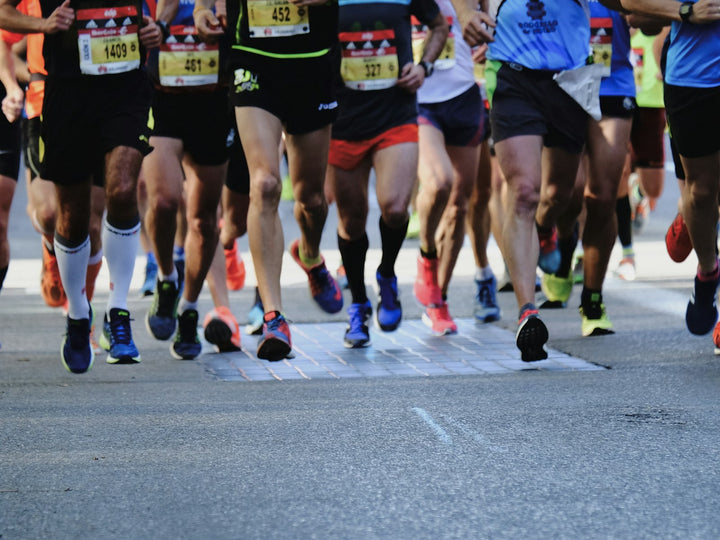 Peloton de coureurs sur route pendant une course, vu à hauteur de jambes